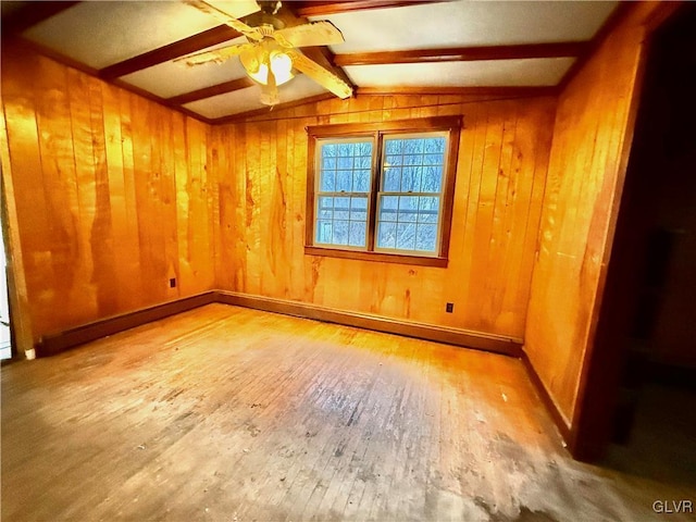 empty room with ceiling fan, wooden walls, vaulted ceiling with beams, and wood-type flooring