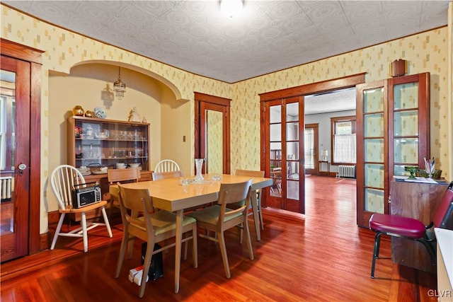 dining area featuring french doors, radiator heating unit, an inviting chandelier, and wood-type flooring