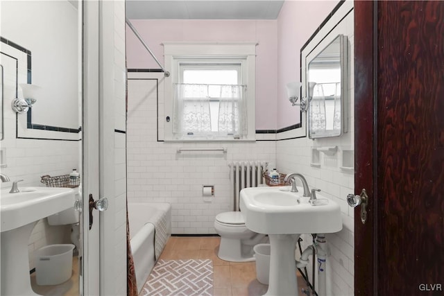 bathroom with radiator, tile patterned floors, sink, toilet, and tile walls