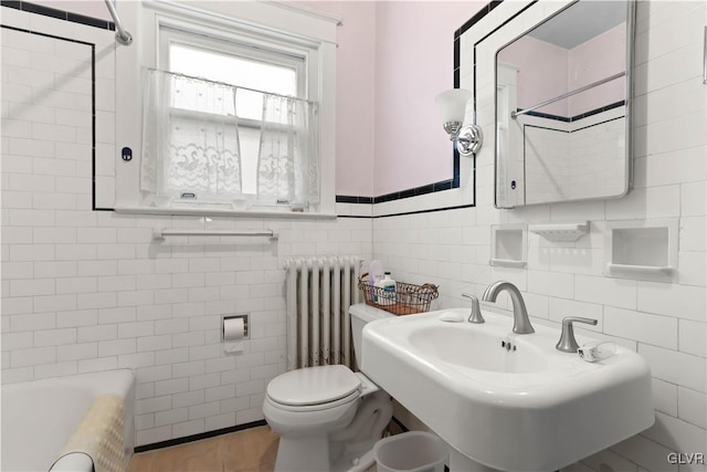 bathroom featuring a washtub, sink, tile walls, radiator heating unit, and toilet