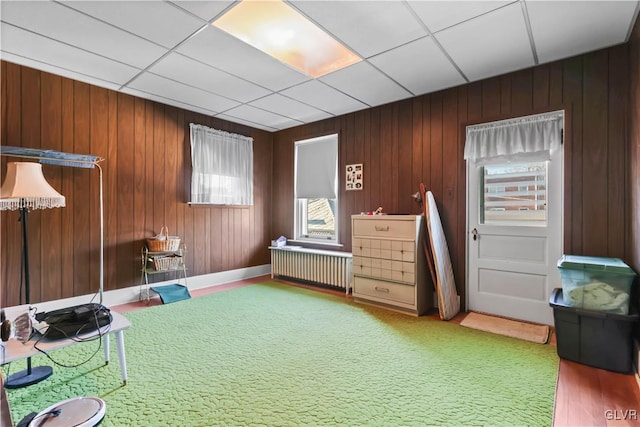 miscellaneous room featuring radiator, wood walls, a drop ceiling, and carpet floors