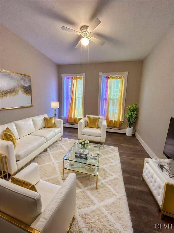 living room featuring baseboard heating, ceiling fan, and dark wood-type flooring