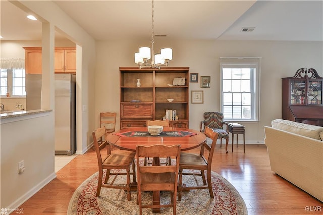 dining space featuring sink, an inviting chandelier, and light hardwood / wood-style floors