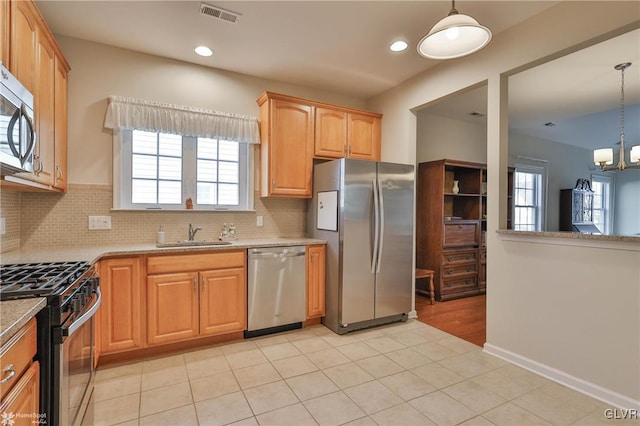 kitchen featuring hanging light fixtures, stainless steel appliances, a notable chandelier, backsplash, and sink