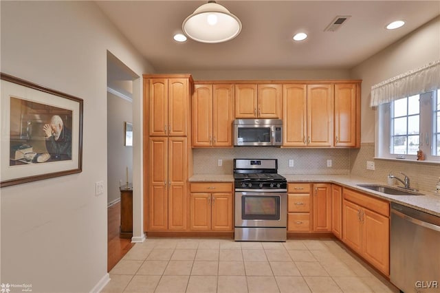 kitchen with stainless steel appliances, sink, tasteful backsplash, and light stone countertops