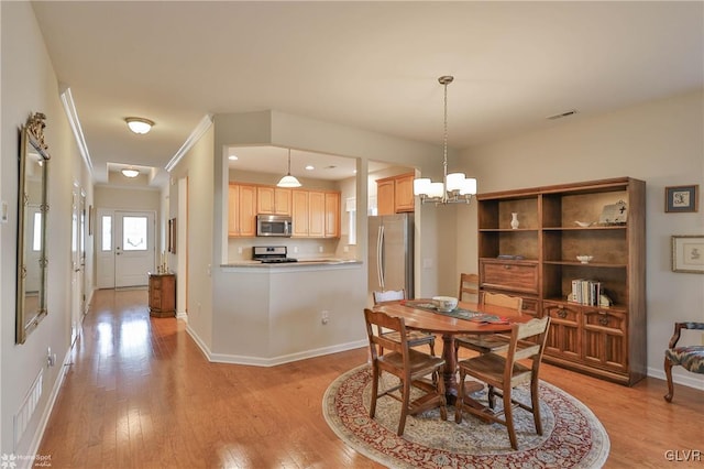 dining room with light hardwood / wood-style floors, an inviting chandelier, and ornamental molding