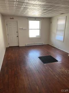 unfurnished room with dark hardwood / wood-style flooring and a baseboard radiator