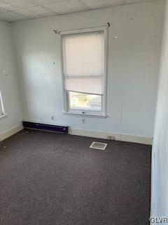 carpeted empty room featuring baseboard heating