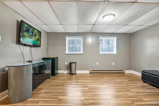 living room with light hardwood / wood-style flooring, a drop ceiling, and a baseboard radiator