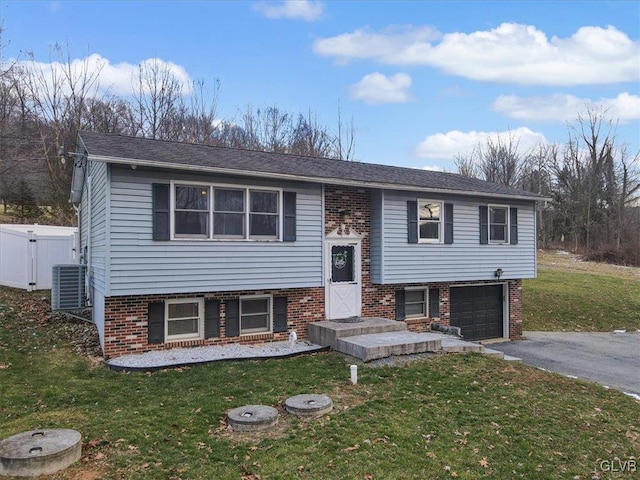 split foyer home with a garage, a front yard, and central air condition unit