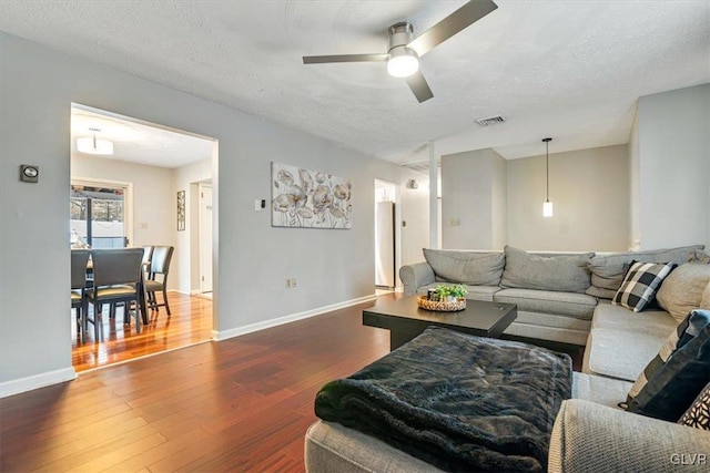 living room with a textured ceiling, ceiling fan, and hardwood / wood-style flooring