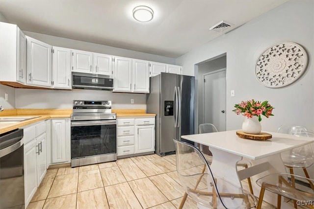 kitchen with appliances with stainless steel finishes, white cabinets, and sink