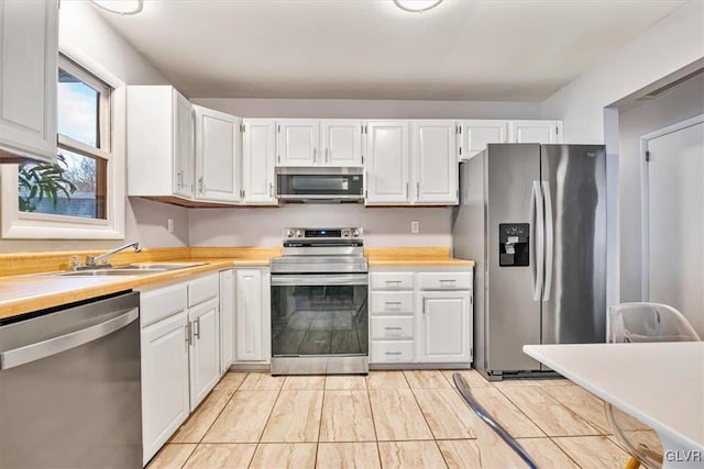 kitchen featuring stainless steel appliances, white cabinets, and sink