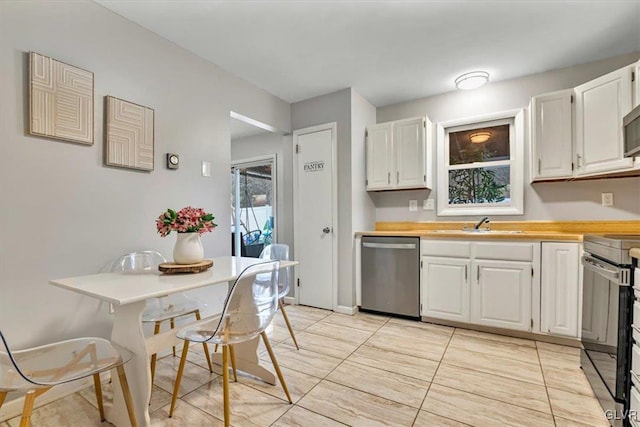 kitchen with white cabinetry, wooden counters, stainless steel appliances, light tile patterned flooring, and sink