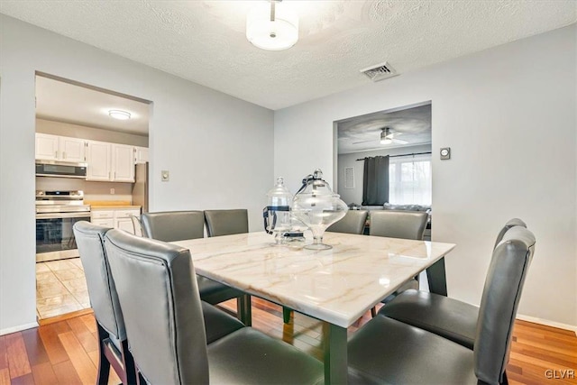 dining space with ceiling fan, a textured ceiling, and hardwood / wood-style flooring