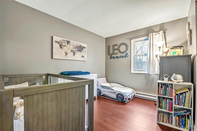 bedroom with dark wood-type flooring and a baseboard radiator