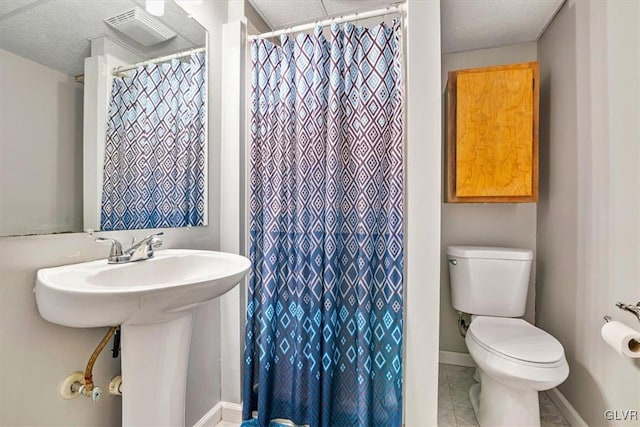 bathroom with a textured ceiling, toilet, and walk in shower