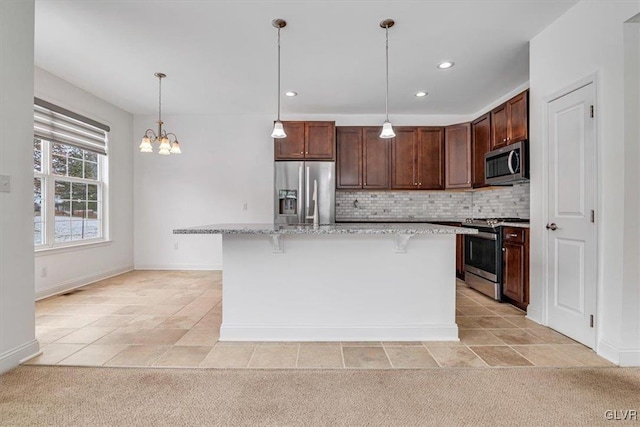 kitchen with stainless steel appliances, decorative light fixtures, a kitchen bar, decorative backsplash, and a kitchen island