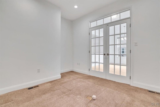 spare room with light colored carpet and french doors