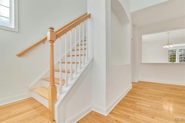 stairs featuring hardwood / wood-style floors and an inviting chandelier