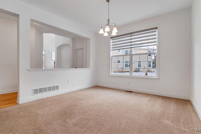 spare room with an inviting chandelier and carpet