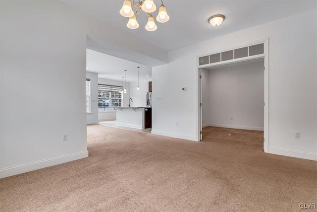 empty room with a notable chandelier, light colored carpet, and sink