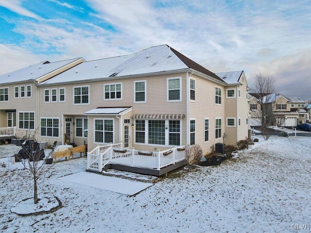 snow covered house featuring central AC unit and a wooden deck