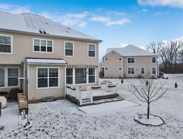 snow covered rear of property with a wooden deck