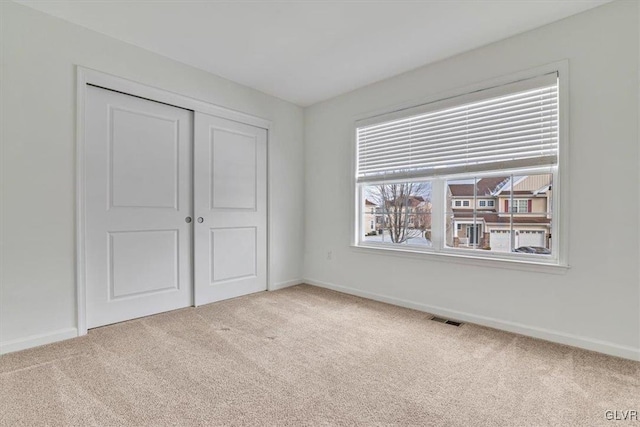 unfurnished bedroom with a closet and light carpet