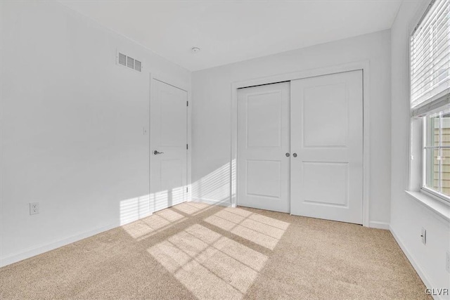 unfurnished bedroom featuring light colored carpet and a closet