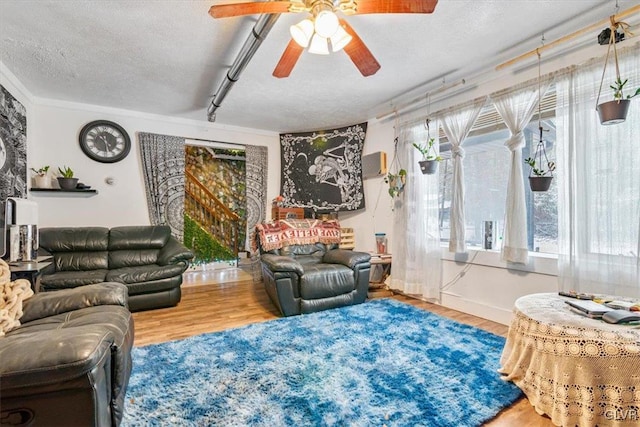 living room with a textured ceiling, hardwood / wood-style floors, ceiling fan, and crown molding