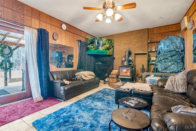 living room with light tile patterned flooring, wood walls, ceiling fan, and a wealth of natural light