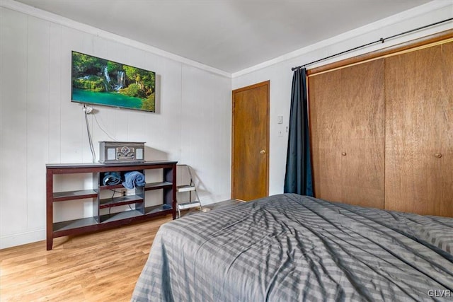 bedroom featuring a closet, crown molding, and wood-type flooring