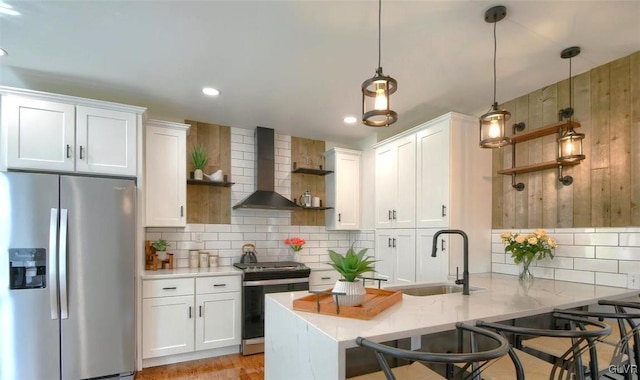 kitchen with stainless steel appliances, white cabinetry, wall chimney range hood, and a kitchen breakfast bar