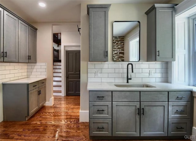 kitchen featuring dark hardwood / wood-style flooring, sink, decorative backsplash, and gray cabinetry