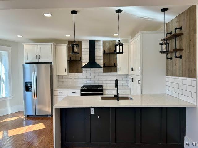 kitchen with white cabinetry, a sink, stainless steel refrigerator with ice dispenser, and wall chimney exhaust hood