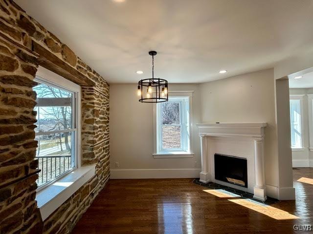 unfurnished dining area with a fireplace with flush hearth, dark wood-style flooring, and a wealth of natural light