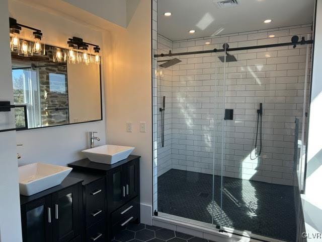 bathroom featuring a stall shower, visible vents, a sink, and double vanity