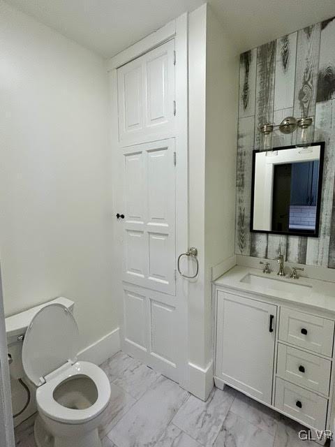 bathroom featuring toilet, marble finish floor, baseboards, and vanity