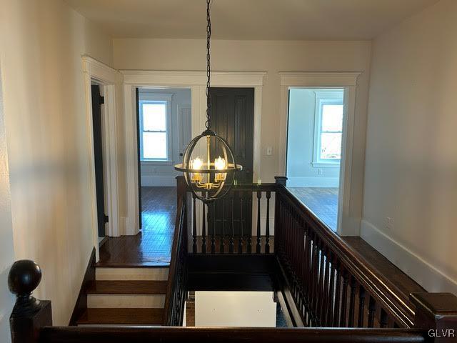 stairway with a chandelier, wood finished floors, and a wealth of natural light