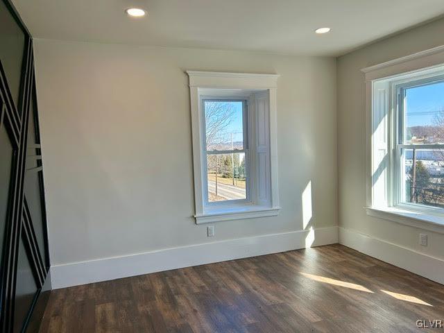 unfurnished room with recessed lighting, dark wood finished floors, and baseboards