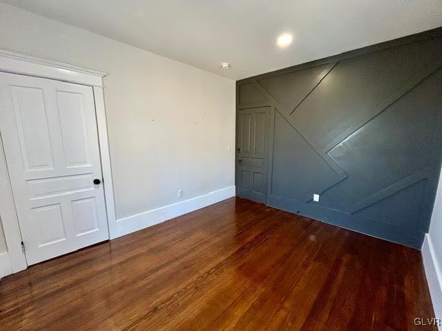 spare room featuring dark wood finished floors and baseboards