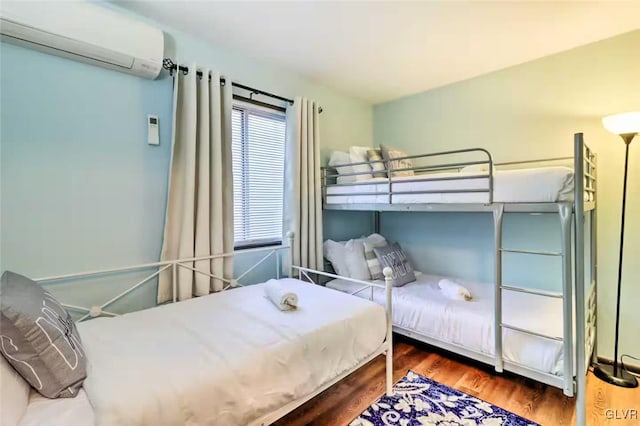 bedroom featuring a wall mounted air conditioner and hardwood / wood-style flooring