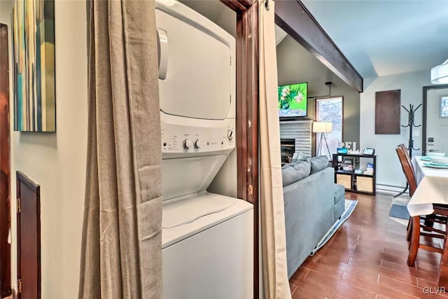 washroom featuring stacked washing maching and dryer, a baseboard heating unit, and dark hardwood / wood-style floors