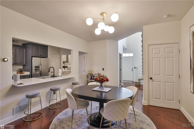 dining room featuring sink, a notable chandelier, and dark wood-type flooring