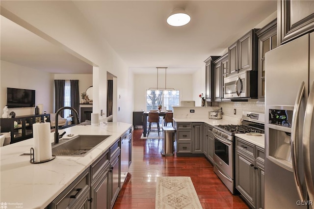 kitchen with a chandelier, stainless steel appliances, dark hardwood / wood-style flooring, pendant lighting, and sink