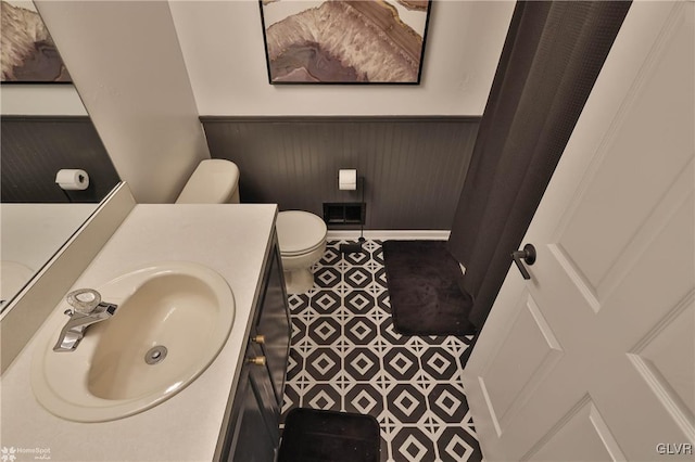 bathroom featuring wooden walls, vanity, and toilet