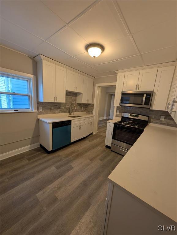 kitchen featuring stainless steel appliances, white cabinetry, backsplash, and dark hardwood / wood-style floors