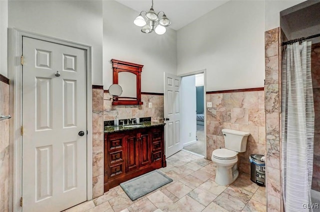 bathroom with toilet, tile walls, an inviting chandelier, a shower with shower curtain, and vanity