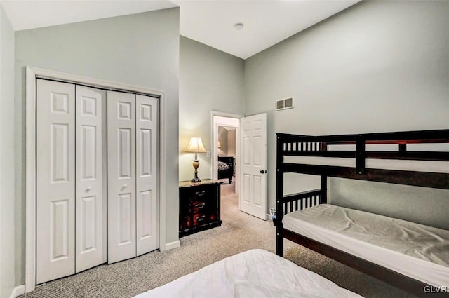 bedroom featuring high vaulted ceiling, a closet, and light carpet